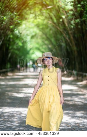 Asian Woman In Yellow Dress And Hat Traveling At Green Bamboo Tunnel, Happy Traveler Walking Chulabh