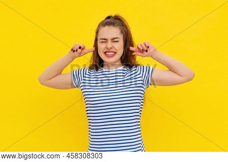 Portrait Of Stressed Brunette Young Woman Plugging Ears With Fingers And Closing Eyes Tight, Irritat