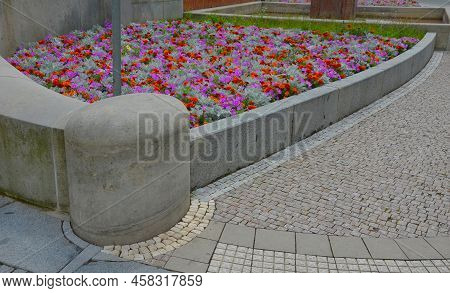 Crazy Annual Bed With A Pink-orange Combination Of Flowers. Large Retaining Walls Of Rounded Sandsto