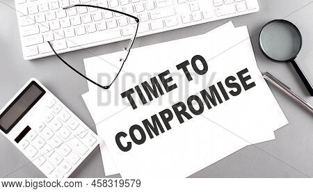 Time To Compromise Text On Paper With Keyboard, Calculator On A Grey Background