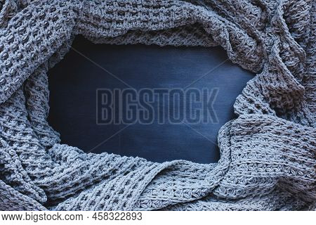 Grey Woven Blanket Crumpled And Framed Over A Dark Toned Black Wooden Background. Shot From Above To