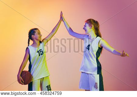 Happy Girls, Basketball Players In Action Isolated On Neoned Background. Concept Of Sport, Team, Ene