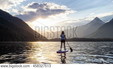 Adventurous Woman Paddle Boarding In A Lake Around Canadian Mountain Landscape. Chilliwack Lake, Bri