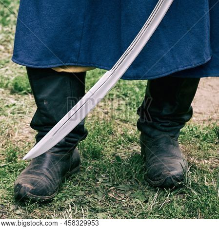 A Man In A Vintage Swedish Military Uniform With A Saber In His Hands. Reconstruction Of The Events 