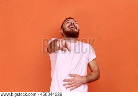 Portrait Of Funny Positive Bearded Man Laughing Out Loud Holding Belly And Pointing Finger On You, M
