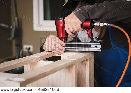 Entrepreneur Woodwork Holding A Tacker To Assemble The Wood Pieces As The Customer Ordered