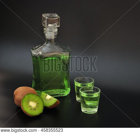 Kiwi-based Liqueur, Strong Homemade Alcohol And Pieces Of Ripe Fruit On A Black Background.