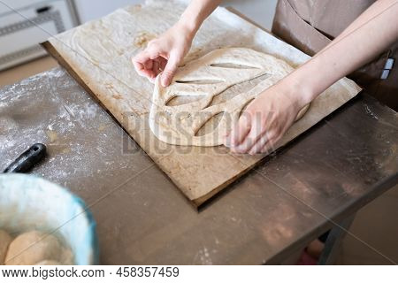 A Baker Shapes And Cuts Traditional French Fougasse Bread. Front View.