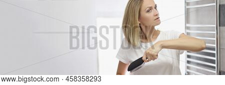 Portrait Of Young Blonde Woman Looking In Mirror And Brushing Hair In Bathroom, No Makeup, Morning R