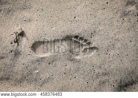 The Footprint Of A Person In The Wet Sand On The Beach.