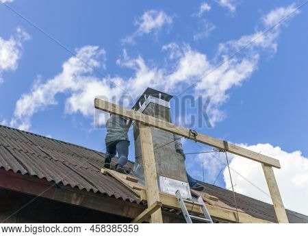 Two Workers Standing On Rooftop And Maintaing Chimney, Blue Sky In The Background