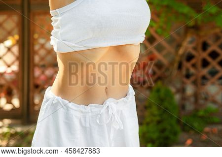 Young Woman Practices Yoga In The Summer Garden. Vacuum Exercise. Nauli Is One Of The Kriyas Or Shat