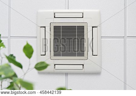 Closeup Cassette Air Conditioner On Ceiling In Modern Light Office Or Apartment With Green Ficus Pla