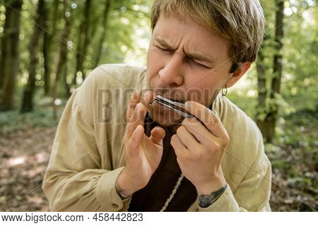 Tattooed Man Playing Jews Harp In Forest