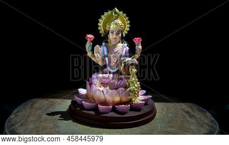 Hindu Cosmos Maha Laxshmi Statue Decorated With Flower Garland On Black Background. Statue Of Goddes