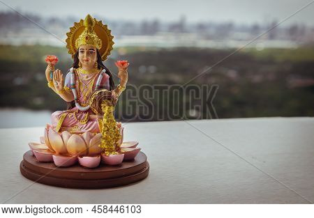 Hindu Cosmos Maha Laxshmi Statue Decorated With Flower Garland With Nature Background. Statue Of God