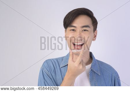 Young Smiling Man Holding Invisalign Braces Over White Background Studio, Dental Healthcare And Orth