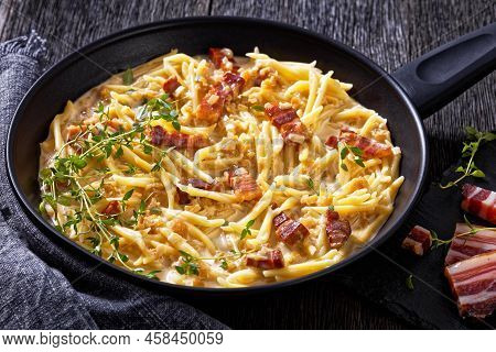 Close-up Of Capunti Pasta In Cream Pecorino Cheese And Pancetta Sauce On Pan On Dark Wooden Table