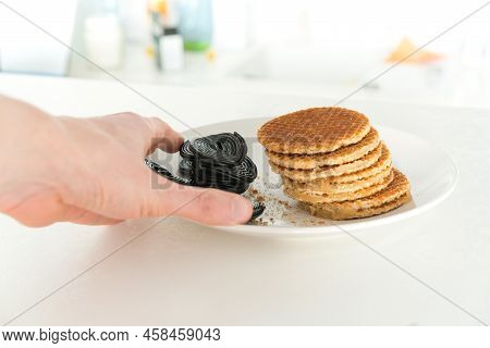 Man's Hand Holds A Plate Of Stroopwafels Or Caramel-filled Traditional Dutch Waffles And A Heap Of L