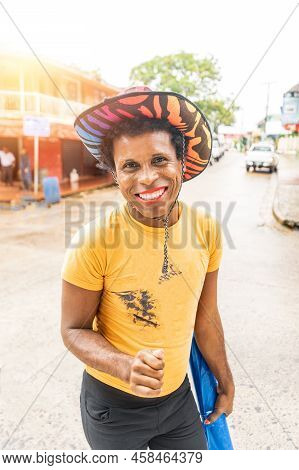 Vertical Photo Of A Black Skinned Latin Gay Man With Colorful Hat Smiling And Looking At Camera