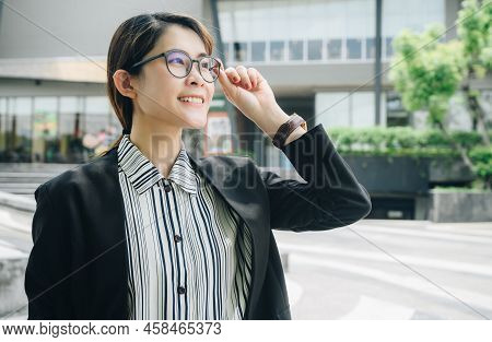 Asian Confident Businesswoman Touching Her Eyeglasses While Standing Outside Her Office. Conceptual 