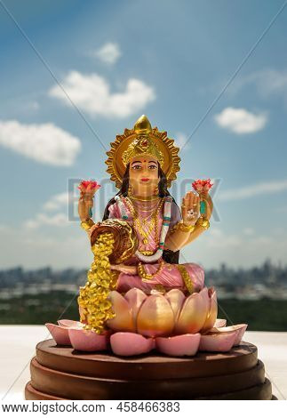 Hindu Cosmos Maha Laxshmi Statue Decorated With Flower Garland With Nature Background. Statue Of God