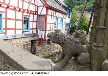 Eifel Village Monreal With Half-timber Houses And Bridge Across River Elsbach With Animal Stone Scul