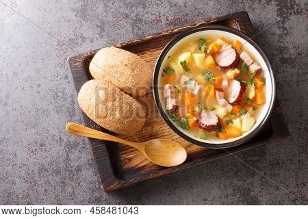 Polish Zupa Grochowa Pea Soup With Vegetables, Bacon And Sausages Close-up In A Bowl On The Table. H