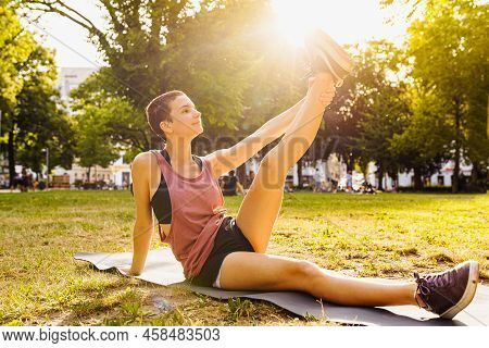 Active Life Of Modern Teenager Of Generation Z. Athletic Teenager Girl Sits On Yoga Mat, Stretches L