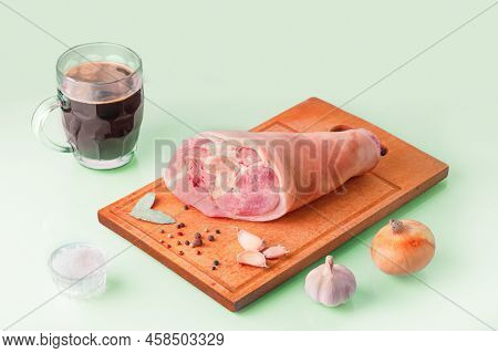 Raw Pork Knuckle, Stout And Other Ingredients For Cooking Baked Pork Knuckle In Beer On Pastel Green