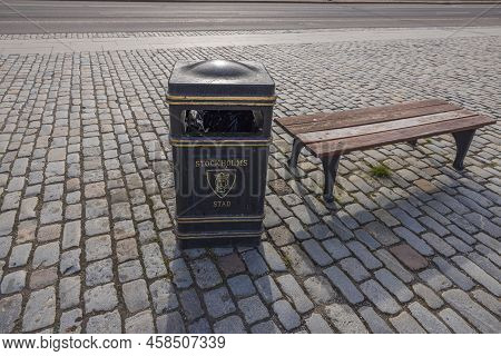 Close Up View Of Garbage Bin Near Bench On Square Covered With Stone Tiles. Stockholm. Sweden. Europ