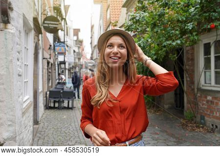 Portrait Of Cheerful Traveler Woman Walking In Schnoor Neighborhood, Bremen, Germany