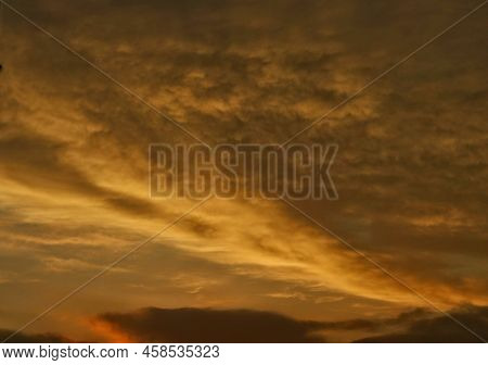 The Outlines Of A Cumulus Cloud Illuminated By The Rays Of The Setting Sun In Warm, Yellow And Orang