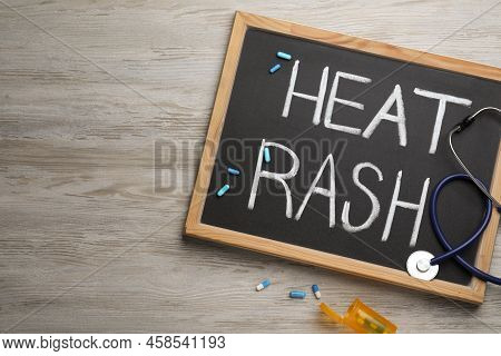 Blackboard With Words Heat Rash, Stethoscope And Pills On Wooden Table, Flat Lay. Space For Text