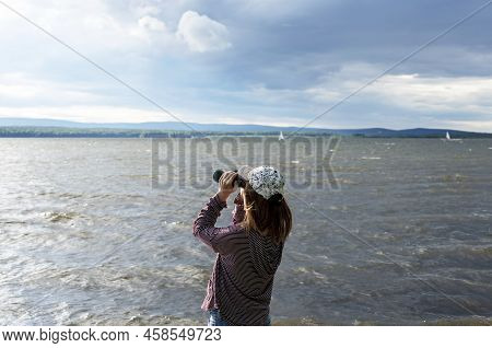 Young Woman In Cap Looking Through Binoculars At Birds On The Lake Or River Birdwatching, Zoology, E