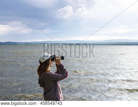 Young Woman In Cap Looking Through Binoculars At Birds On The Lake Or River Birdwatching, Zoology, E