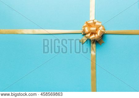 Top View Of Gold Ribbon Rolled And Yellowbow Isolated On Colored Background. Flat Lay With Copy Spac