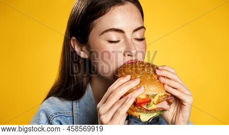 Girl Bites Cheeseburger With Pleasure. Woman Eating Hambuger, Order Burger For Takeaway Food Deliver