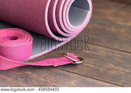Yoga Mat, With Yoga Strap On Wooden Background. Essential Accessories For Practice Yoga And Meditati
