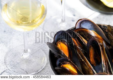 Steamed Mussels  Served In Frying  Pan, Glasses Of White Wine On Cement Background. Popular  Mediter