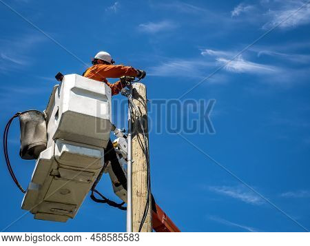 Power Lineman Working From An Insulated Aerial Device Installing A Service On A Beautiful Summers Da
