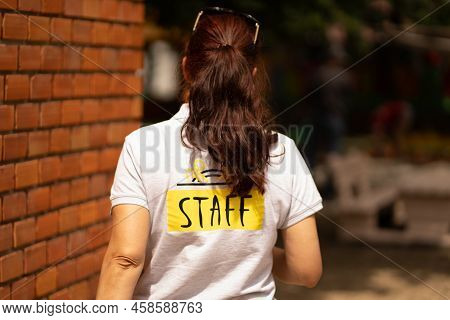 Staff Member Walking Alongside A Brick Wall