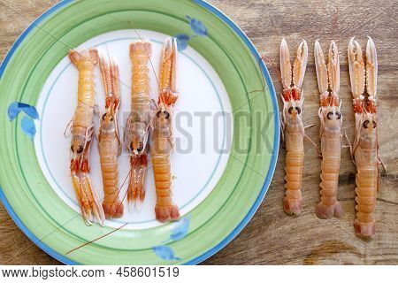 Flat Lay Of Fresh Shrimps On A White Dish And On A Wooden Table