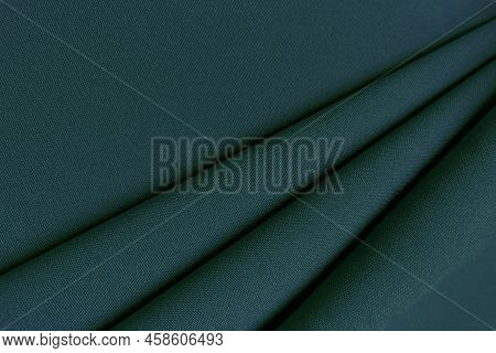 Green Crumpled Or Wavy Fabric Texture Background. Abstract Linen Cloth Soft Waves. Gabardine Wool Fa