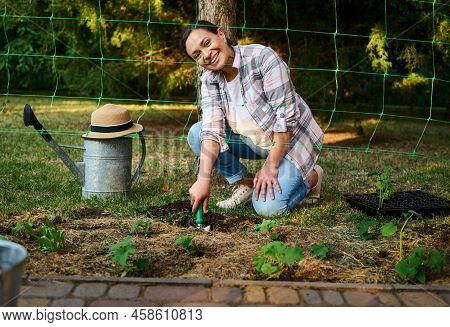 View Through The Net For Tying Cucumbers At A Smiling Farmer Digging A Hole For Planting Seedlings, 
