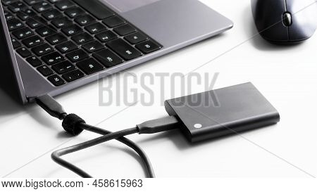 External Portable Ssd Drive Connected To Laptop And Computer Mouse On White Background. Portable Sol
