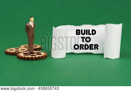 Business Concept. The Figure Of A Man Stands On The Gears And Reads The Inscription - Build To Order