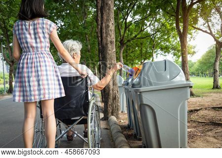 Asian Senior Woman Hand Putting Plastic Water Bottle In Recycling Bin,elderly Tourist In Wheelchair,