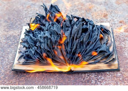 An Open Book Is Burning, An Open Book With Charred Pages On Fire. Burning Books