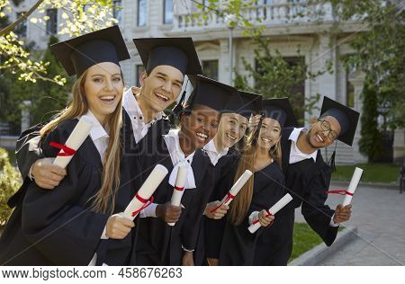 Young Multiracial College Graduates In Academic Gown Pose With Smile After Graduation Ceremony